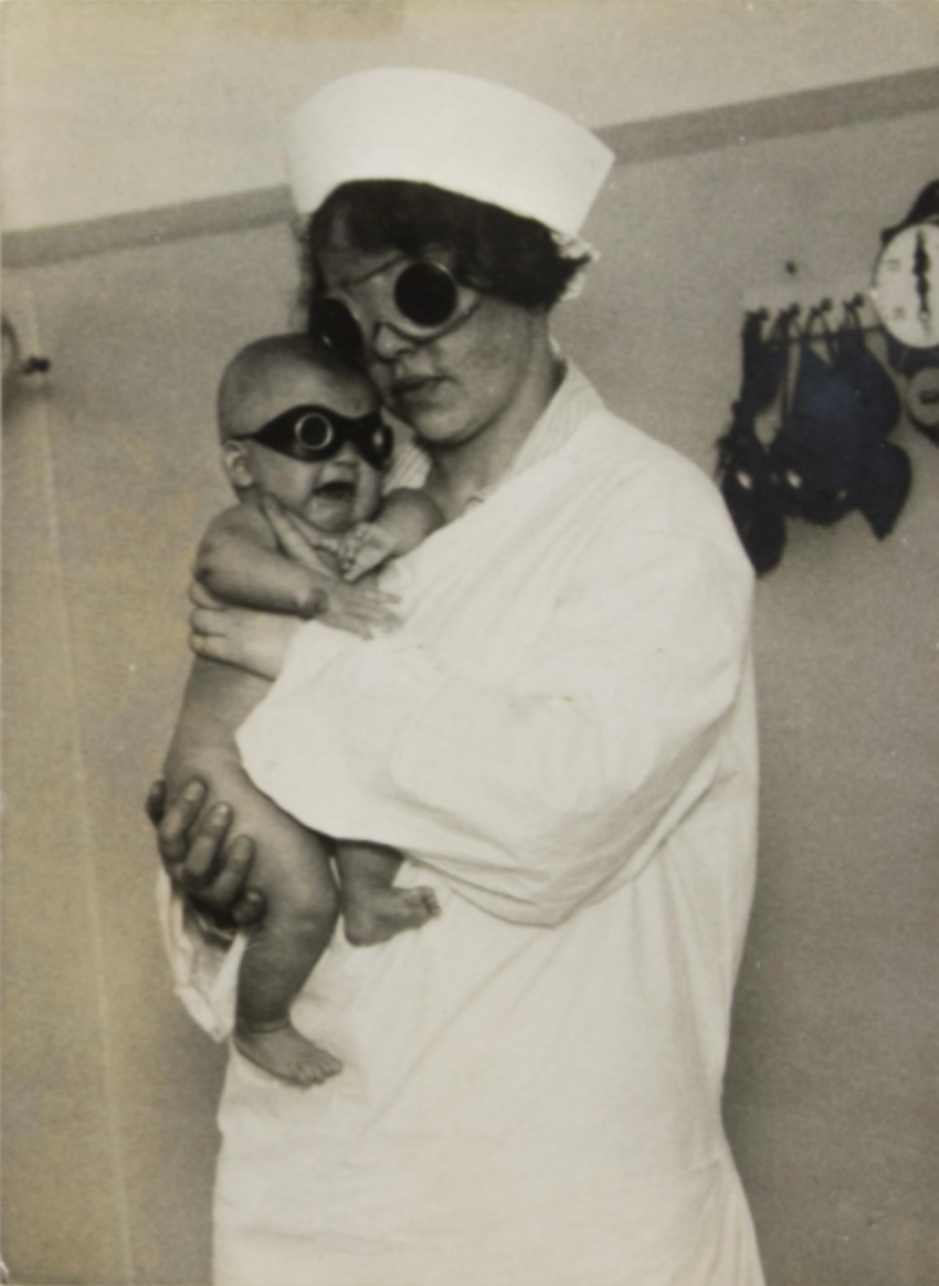 Nurse and baby in protective gas goggles, [Germany], ca. 1930